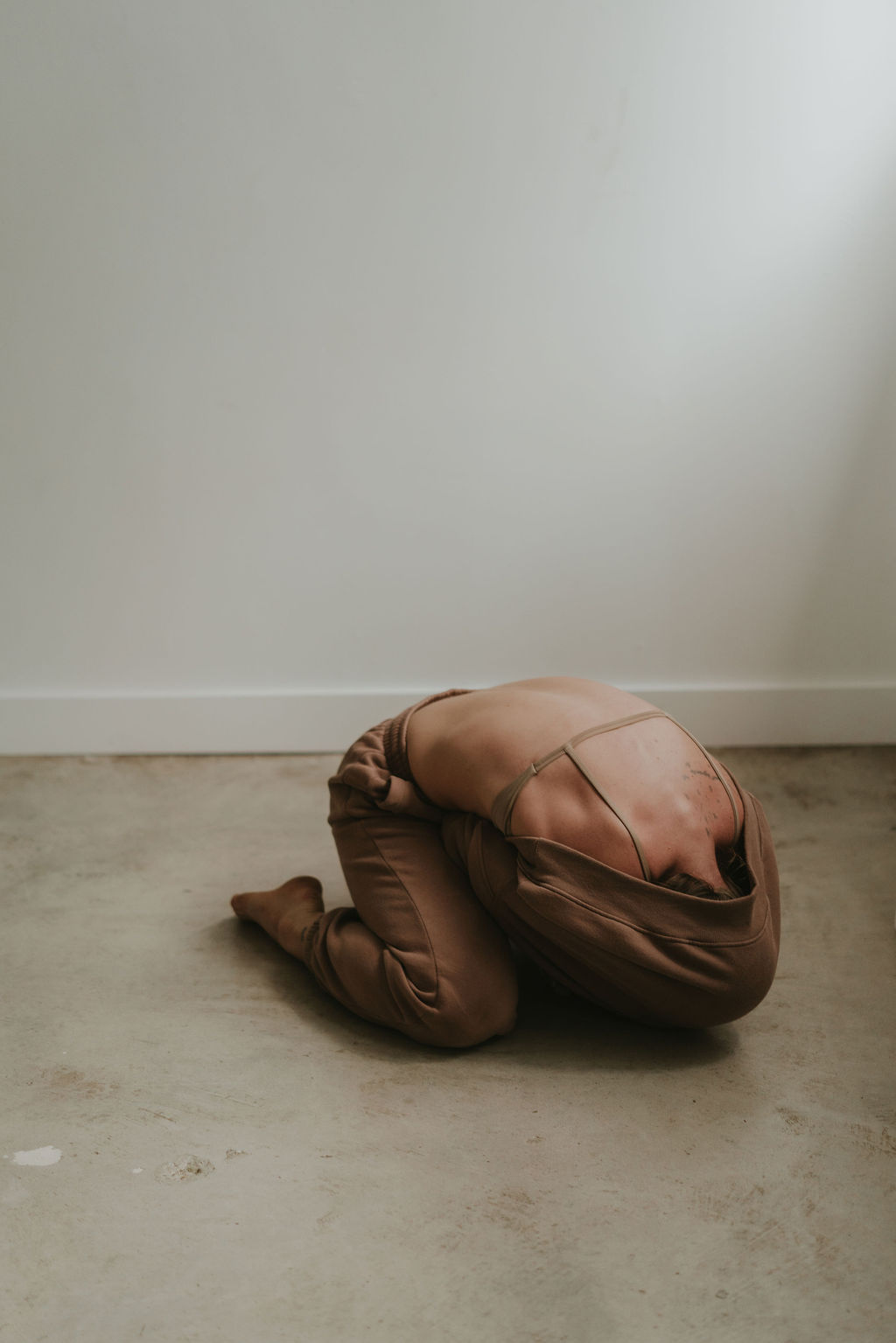 A woman curled on the floor of a quiet studio